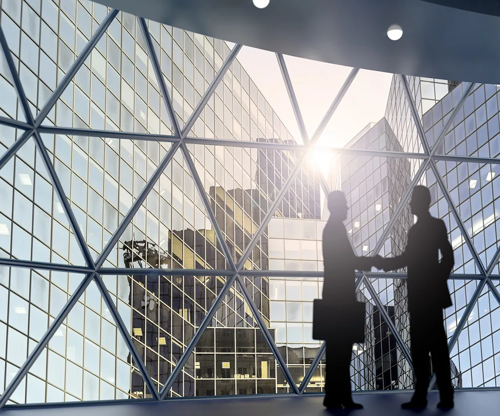 2 business men shaking hands in an office